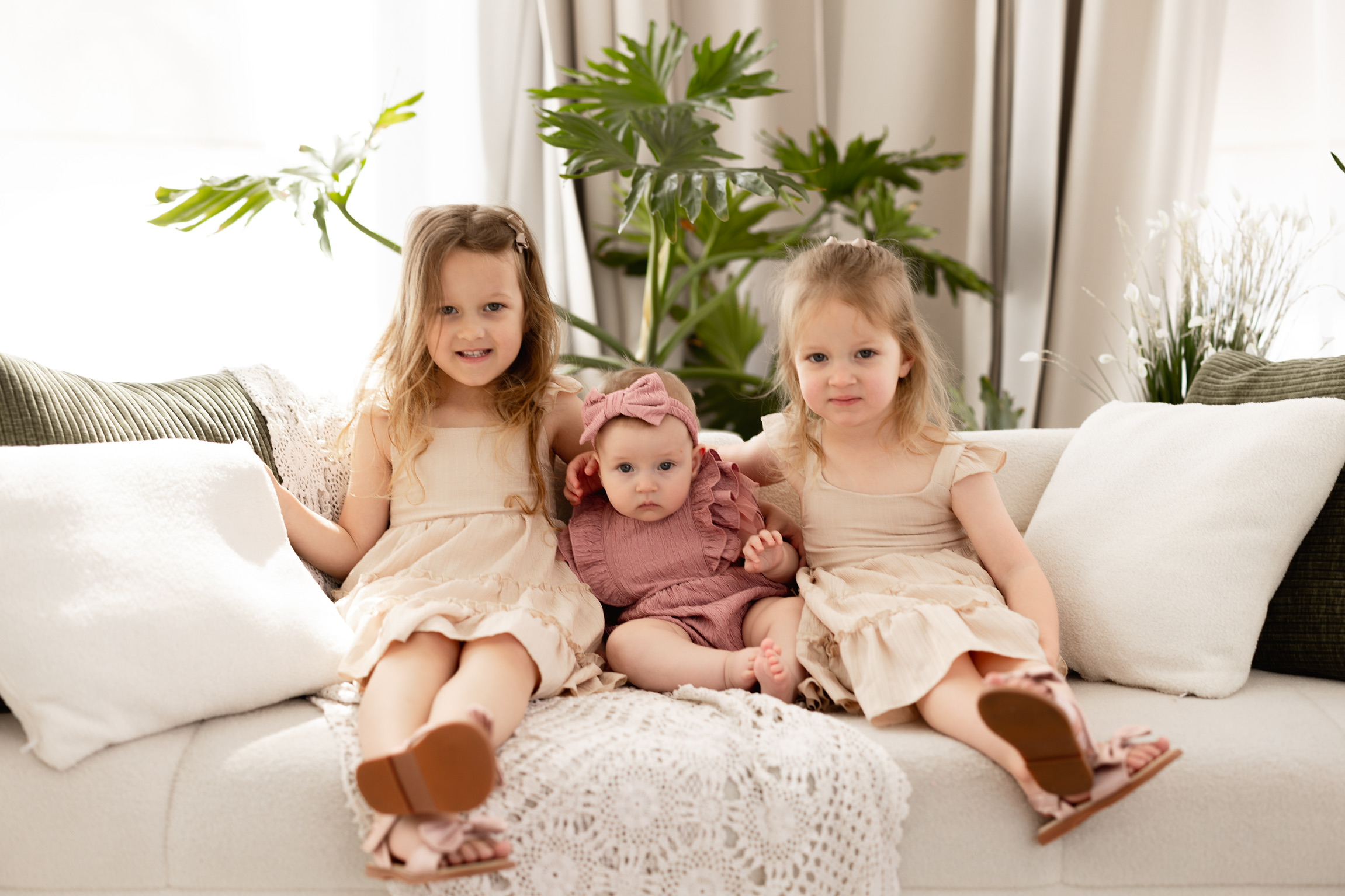 Three young sisters sitting together indoors