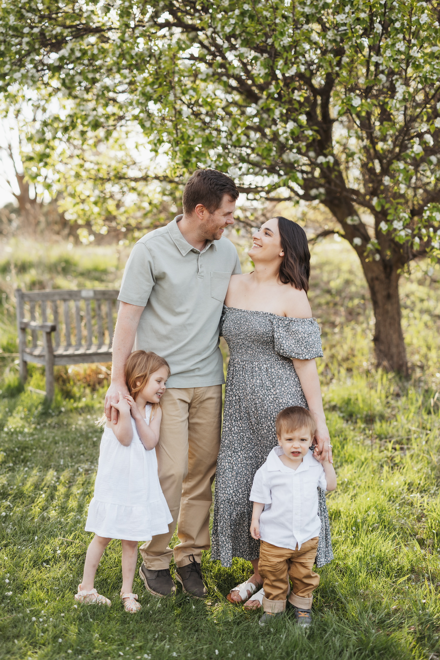 Parents embracing while their daughter and son stand in front of them in the evening sun